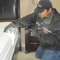 Bed bug inspection technician checking a mattress and bed frame for signs of infestation in Syracuse, NY
