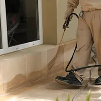 General pest control technician spraying exterior perimeter around a home in Syracuse, NY